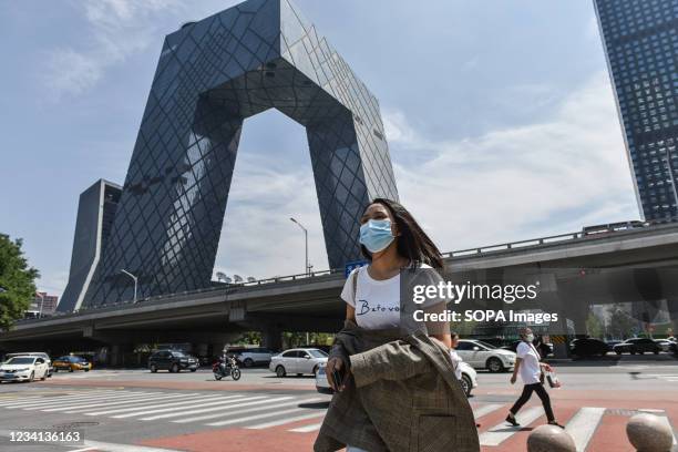 Woman wearing a face mask walks near the CCTV building at the international trade area of Beijing. On Thursday, July 22 a senior Chinese health...