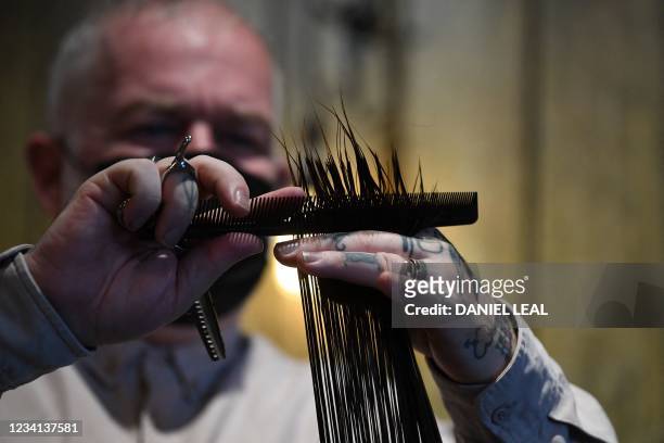 Hair salon owner and hairdresser, Adam Reed cuts the hair of a client at his salon in Spitalfields, east London on July 1 before collecting the hair...