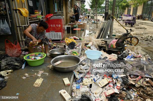 Woman cleans some belongings following heavy rain which caused flooding earlier in the week that claimed at least 56 lives, in the city of Zhengzhou...