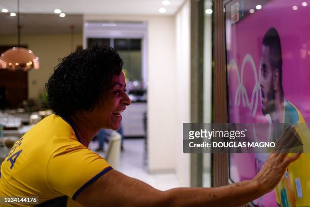 Rosa Maria, mother of Brazilian volleyball player Ricardo Lucarelli, watches TV where her son participates in the Olympic games, from the family's...