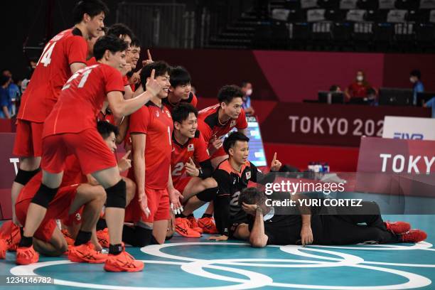 Japan's team pose after their victory in the men's preliminary round pool A volleyball match between Japan and Venezuela during the Tokyo 2020...