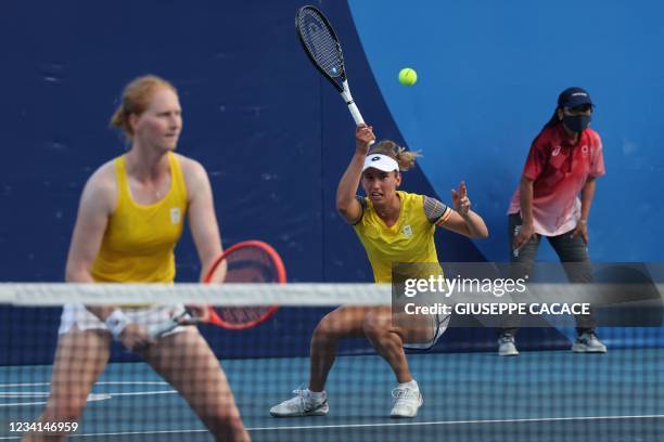 Belgium's Elise Mertens returns a shot to Spain's Carla Suarez Navarro and Spain's Garbine Muguruza during their Tokyo 2020 Olympic Games women's...