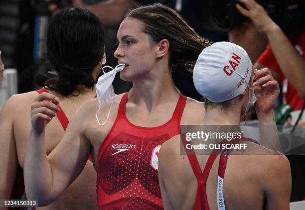 Canada's Penny Oleksiak holds her face mask in her teeth after competing in a heat for the women's 4x100m freestyle relay swimming event during the...