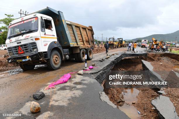 People gather along a road partially washed away from the rain at Mahad on July 24 as the death toll from heavy monsoon rains climbed to 79, with...