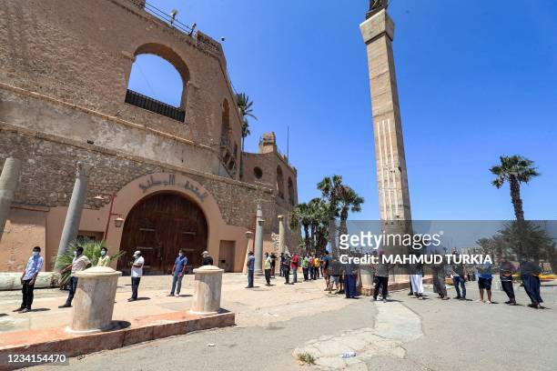 People queue past the Red Castle Museum as they arrive outside a make-shift COVID-19 coronavirus vaccination and testing centre erected at the...