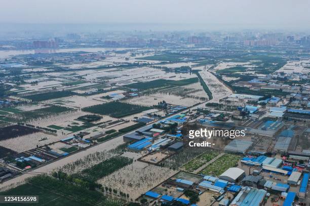This aerial photo taken on July 23, 2021 shows flooded fields and streets following heavy rains in Xinxiang, in China's central Henan province. -...