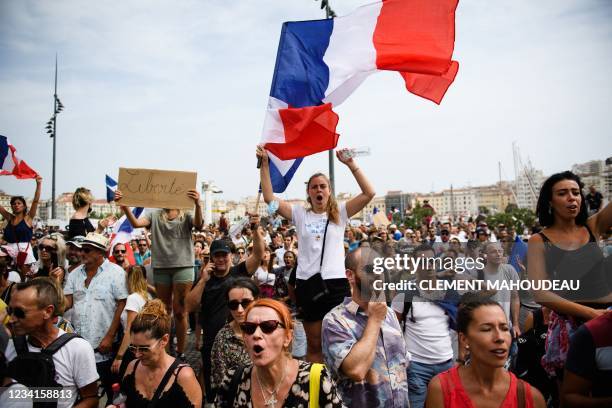 Protestor holds a placard reading "Freedom" while others wave French national flags during a demonstration against the compulsory vaccination for...