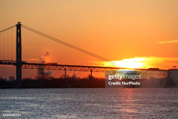 The sun sets behind the Ambassador Bridge over the Detroit River between Detroit, Michigan and Windsor, Ontario, Canada. Windsor-Detroit is the...