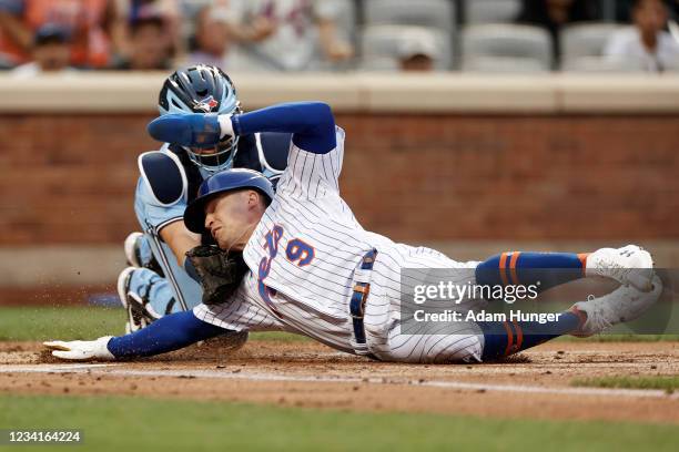 Brandon Nimmo of the New York Mets is tagged out trying to score by Reese McGuire of the Toronto Blue Jays during the first inning at Citi Field on...