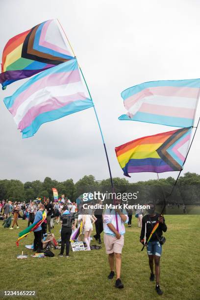 Protesters hold Progress Pride and Transgender Pride flags as the first-ever Reclaim Pride march arrives in Hyde Park for a Queer Picnic on 24th July...