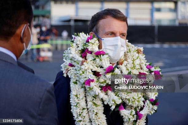 France's President Emmanuel Macron is covered in garlands during a welcoming ceremony upon his arrival at Faa'a international airport for a visit to...