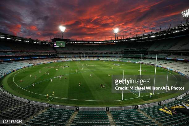 General view as the sun sets during the 2021 AFL Round 19 match between the Geelong Cats and the Richmond Tigers at the Melbourne Cricket Ground on...