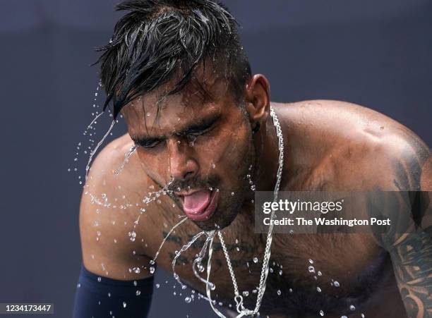 India's Sumit Nagal shakes water off after pouring water on his head to cool down during a heat break while playing a qualifying match against...