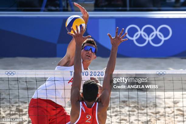 Poland's Michal Bryl hits a shot as Morocco's Zouheir Elgraoui blocks in their men's preliminary beach volleyball pool E match between Poland and...