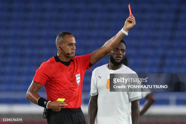 Referee Ismail Elfath shows a red card after a second yellow card to Ivory Coast's midfielder Eboue Kouassi during the Tokyo 2020 Olympic Games men's...