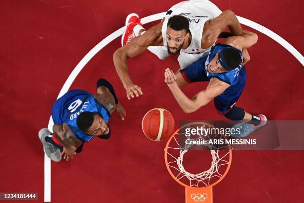 S Damian Lillard looks on as teammate Devin Booker fights for a rebound with France's Rudy Gobert during the men's preliminary round group A...