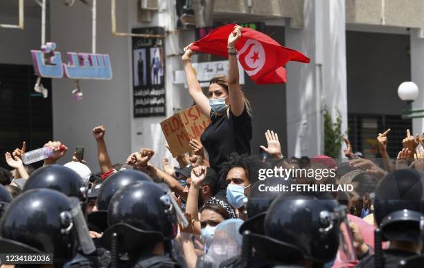 Tunisian protester lifts a national flag at an anti-government rally as security forces block off the road in front of the Parliament in the capital...
