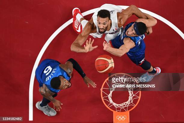 S Damian Lillard looks on as teammate Devin Booker fights for a rebound with France's Rudy Gobert during the men's preliminary round group A...