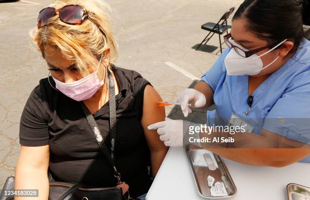 Socorro Santamaria, twin sister of Auxiliadora Gutierrez gets the Covid vaccine from Registered Nurse Priscilla at the Pico Union Project located at...