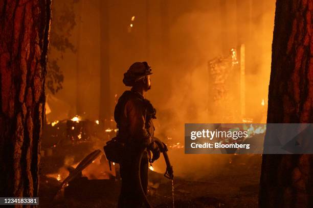 Firefighter monitors a fire as multiple structures burn in the Indian Falls neighborhood during the Dixie Fire near Crescent Mills, California, U.S.,...