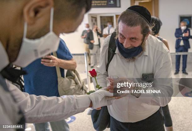 Israeli tourists receive a rose and a welcome beverage upon arrival at Marrakech-Menara International Airport after taking the first commercial...