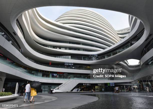 People walk near the galaxy SOHO shopping center in Beijing. Galaxy SOHO is located in East 2nd Ring Road, near Chaoyangmen, Beijing. It was...