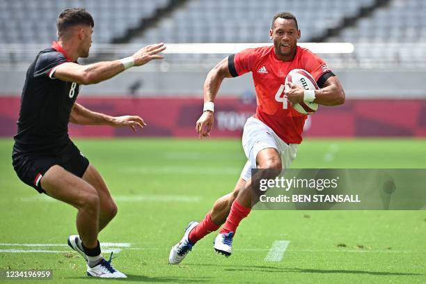 Britain's Dan Norton tries to avoid the tackle of Canada's Justin Douglas in the men's pool B rugby sevens match between Britain and Canada during...