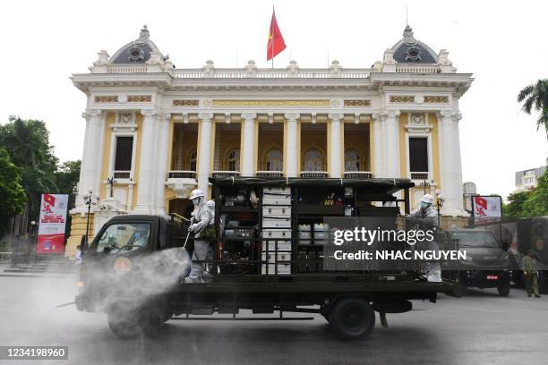 Military personnel spray disinfectant in front of the Opera House in Hanoi on July 26, 2021 as a preventive measure to stop the spread of the...