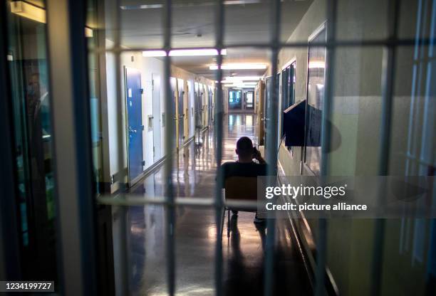 July 2021, Mecklenburg-Western Pomerania, Stralsund: An inmate talks on the phone in the cell corridor at the correctional facility . Corona...