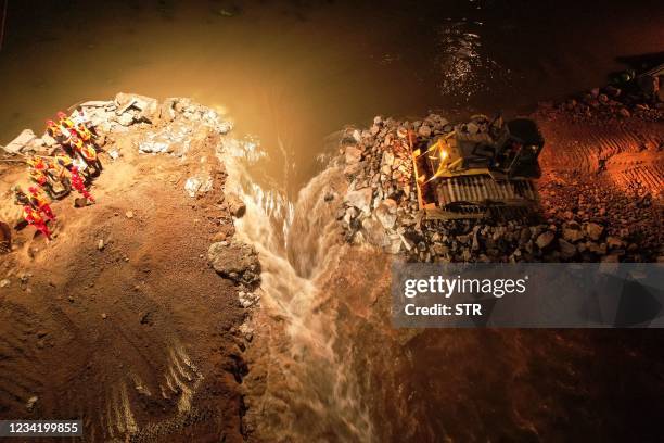 This aerial photo taken early on July 26, 2021 shows rescuers working to seal a dyke after it was breached by heavy rains in Hebi, in China's central...