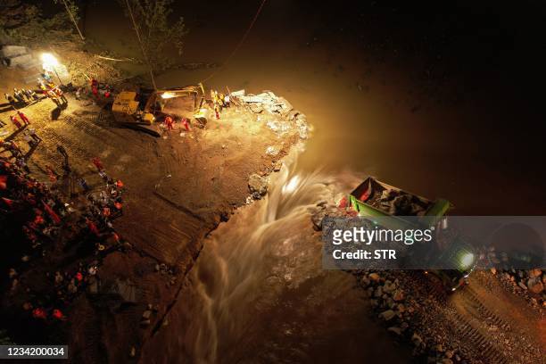 This aerial photo taken on July 26, 2021 shows a truck dumping rocks in floodwaters as rescuers work to seal a dyke after it was breached by heavy...