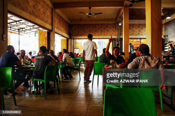 Customers dine at a restaurant in Lhokseumawe, Aceh on July 26 as small shops, streetside restaurants and some shopping malls reopened in...