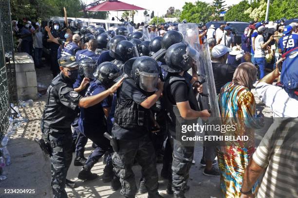 Tunisian security officers hold back protesters outside the parliament building in the capital Tunis on July 26 following a move by the president to...