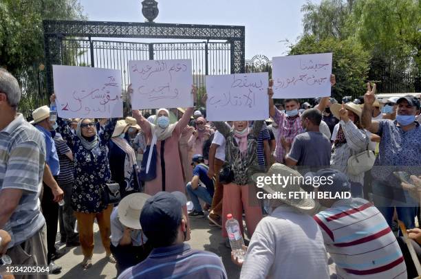 Tunisian protesters hold up placards with slogans denouncing what they described as a "coup d'etat" outside the parliament building in the capital...
