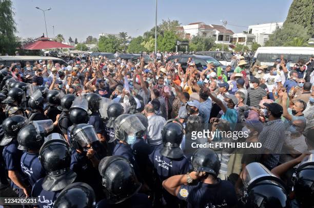 Tunisian security officers hold back protesters outside the parliament building in the capital Tunis on July 26 following a move by the president to...
