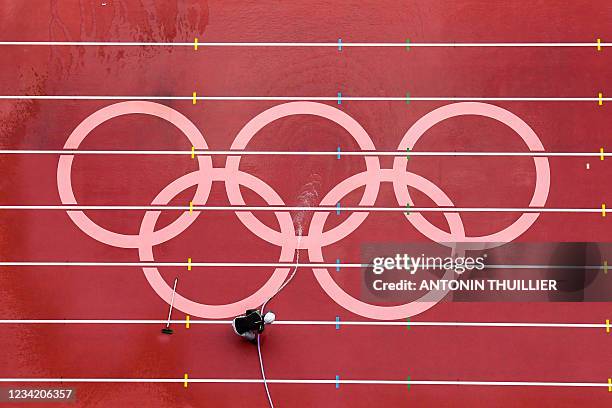 Man washes the track at the Olympic Stadium ahead of the athletics events of the Tokyo 2020 Olympic Games in Tokyo on July 26, 2021.