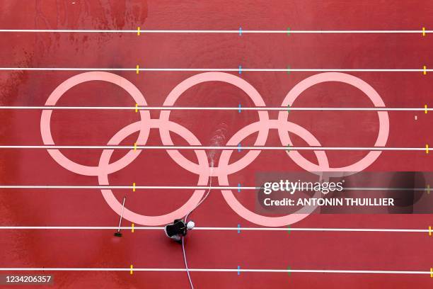 Man washes the track at the Olympic Stadium ahead of the athletics events of the Tokyo 2020 Olympic Games in Tokyo on July 26, 2021.