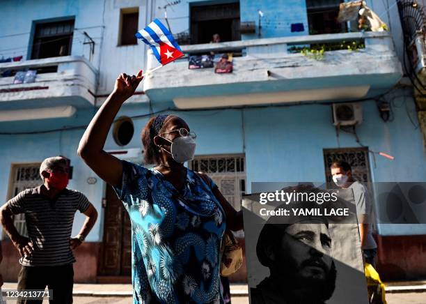 An elderly woman waves a Cuban flag holding a poster of Cuban late leader Fidel Castro in Havana, on July 26, 2021. - The Cuban government on July 26...