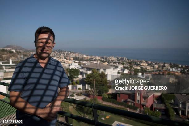 British expat Mike Battle poses on his balcony at home in Malaga on July 21, 2021. - Tens of thousands of expats are separated from friends and...