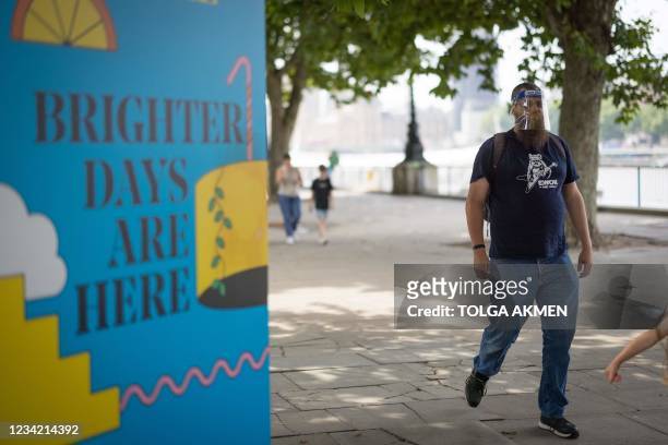 Pedestrian walks past a sign on the southbank in central London on July 26, 2021. - For the first time in the latest wave of coronavirus covid-19...