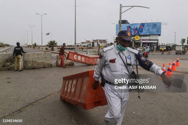 Policemen place barriers near the Clifton beach which was sealed by the authorities amidst rising Covid-19 coronavirus cases in Karachi on July 26,...