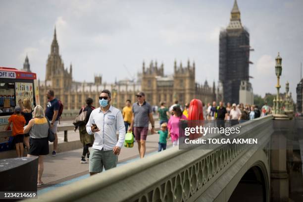 Pedestrians, some wearing face masks cross Westminster Bridge with Elizabeth Tower, better known by the nickname for the Great Bell in the clock Big...