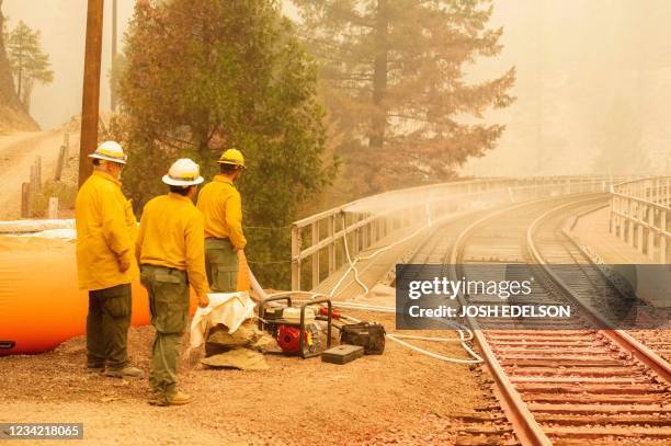 Employees of the Burlington Northern Santa Fe train lines protect train tracks with a mobile sprinkler system during the Dixie fire in Quincy,...