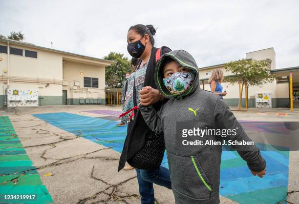 Los Angeles, CA First grade student Daniel Cano and his mom, Sonia Cano, walk past COVID-19 safety precaution/ social distancing and hand washing...