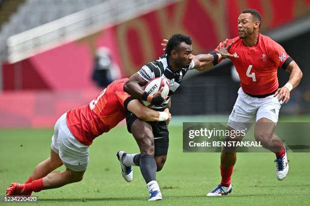 Fiji's Jerry Tuwai is tackled by Britain's Alex Davis and Britain's Dan Norton in the men's pool B rugby sevens match between Fiji and Britain during...