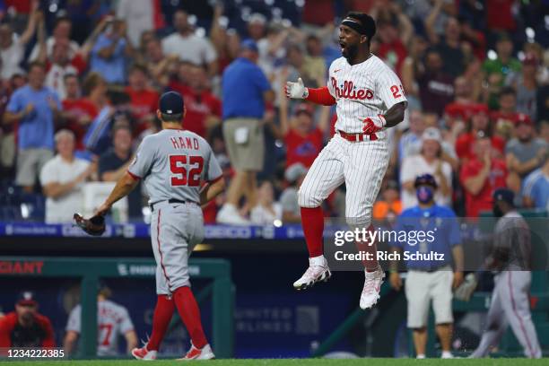 Andrew McCutchen of the Philadelphia Phillies rounds third base while closer Brad Hand of the Washington Nationals walks off the field after...