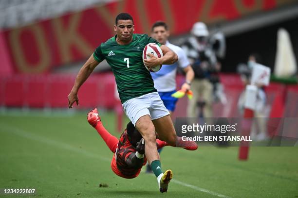 Ireland's Jordan Conroy avoids the tackle of Kenya's Jeff Oluoch in the men's pool C rugby sevens match between Kenya and Ireland during the Tokyo...