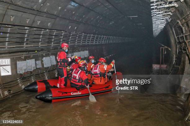 This photo taken on July 26, 2021 shows rescuers searching inside the subway which was flooded following heavy rains in Zhengzhou, in China's central...