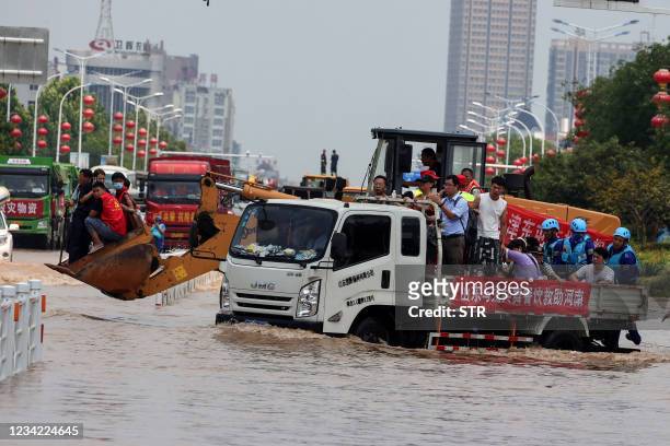 This photo taken on July 26, 2021 shows rescuers evacuating residents with a truck at a flooded area in Weihui, Xinxiang city, in China's central...