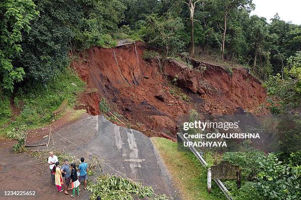 In this picture taken on July 26 onlookers gather near the site of a landslide due to ongoing heavy monsoon rains at Yellapur in the Uttara Kannada...